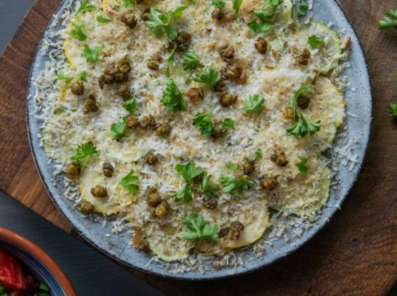 Courgette Carpaccio With Parmesan, Walnut And Crispy Caper Berries served on a plate